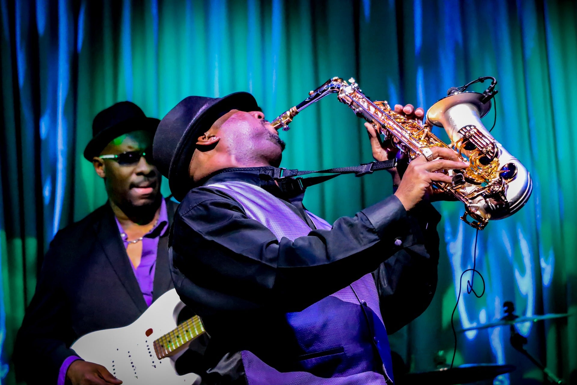 Two musicians playing guitar and saxophone.